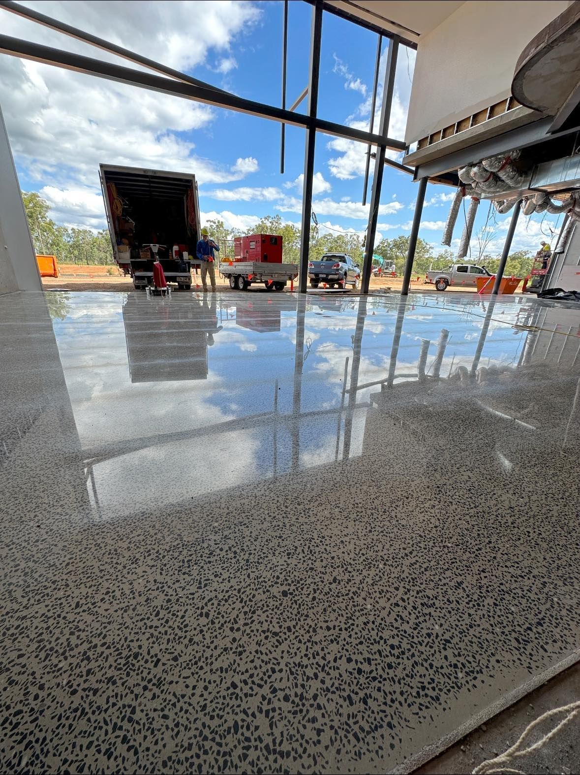 Highly polished concrete floor reflects trucks and sky through large windows; construction site. — Showcase Concrete & Polishing in Moore Park Beach, QLD