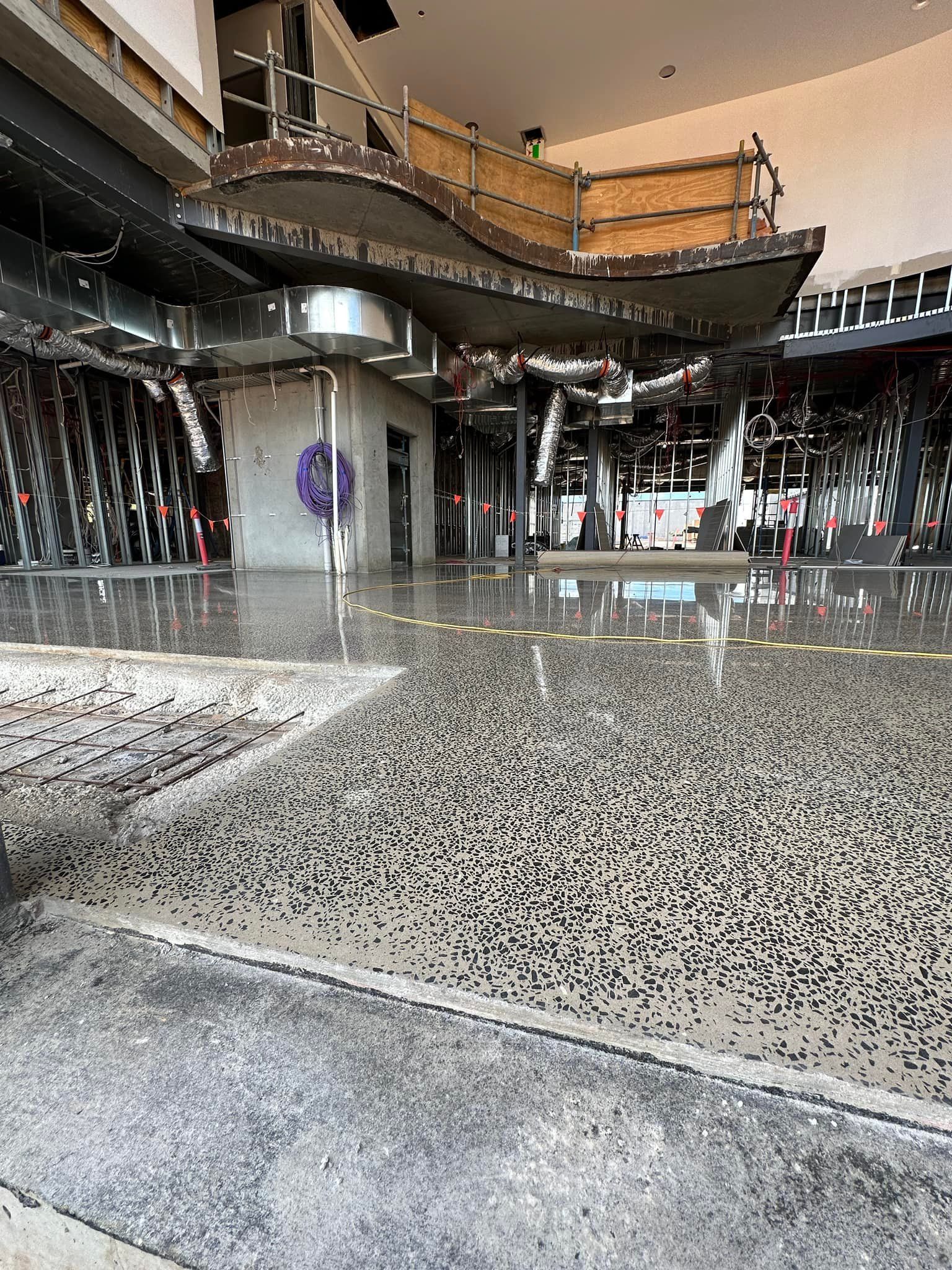 Polished concrete floor in a building, with a curving structure above and a small structure in the center. — Showcase Concrete & Polishing in Moore Park Beach, QLD