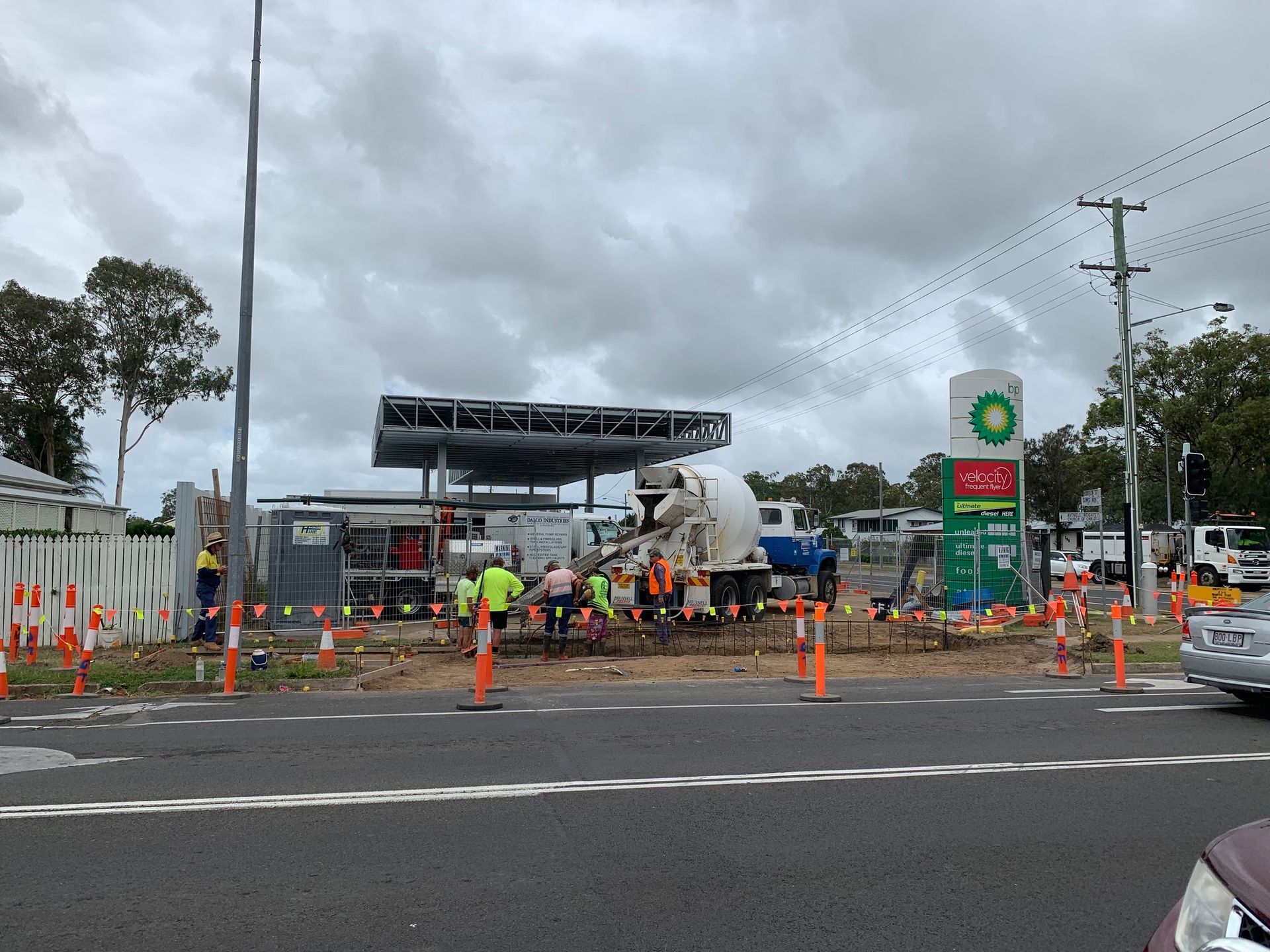 Construction at a BP gas station. Workers near a concrete mixer and canopy under an overcast sky. — Showcase Concrete & Polishing in Moore Park Beach, QLD