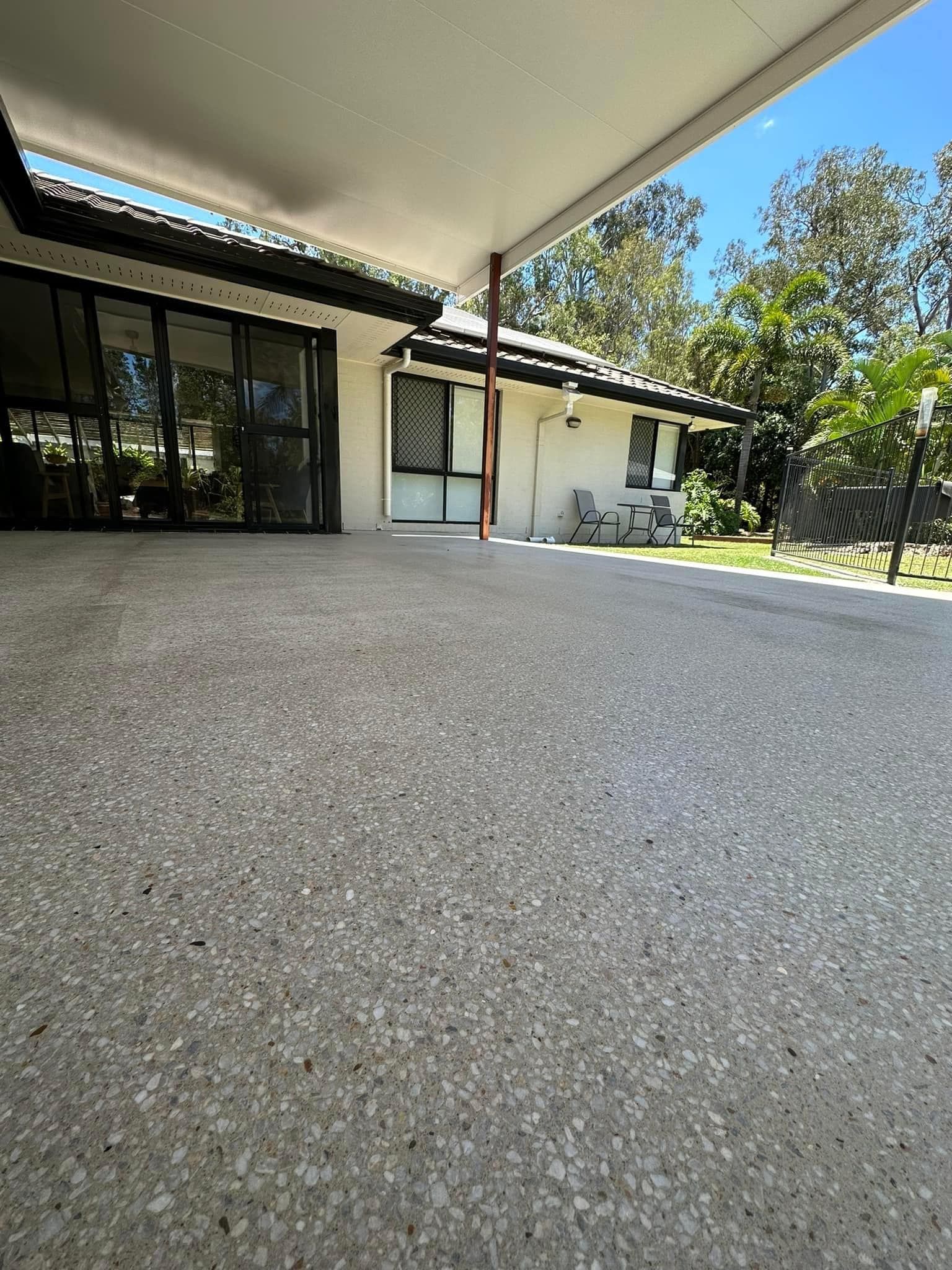Concrete patio with covered area, view of a house, trees, and blue sky. — Showcase Concrete & Polishing in Moore Park Beach, QLD