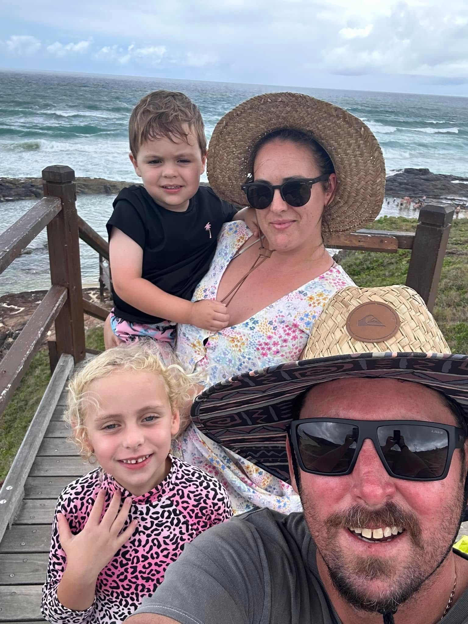Family of Three Smiles at Camera in Front of a Clock — Showcase Concrete & Polishing in Moore Park Beach, QLD