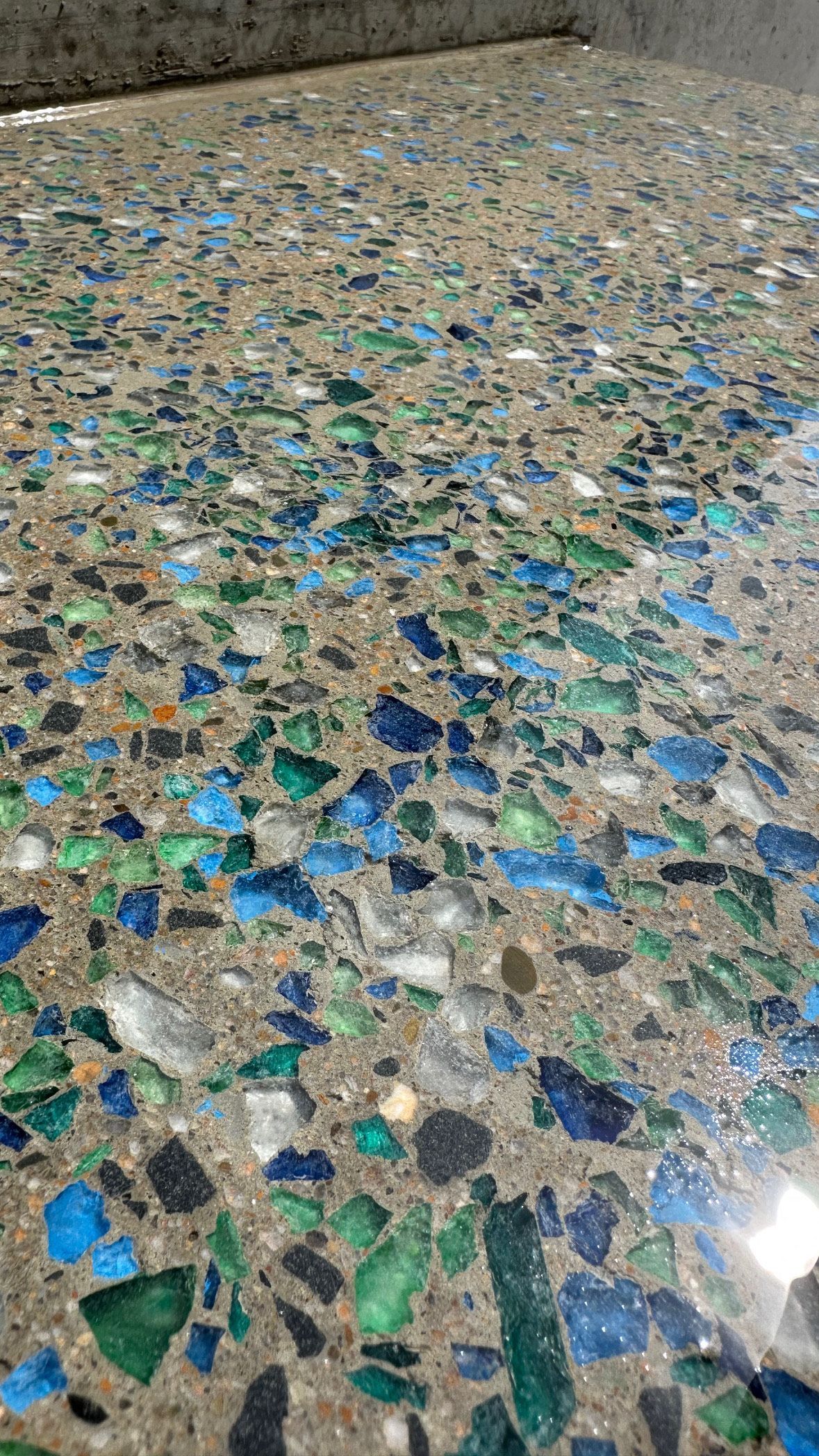 Close-up view of a concrete floor inlaid with blue and green glass shards. — Showcase Concrete & Polishing in Moore Park Beach, QLD