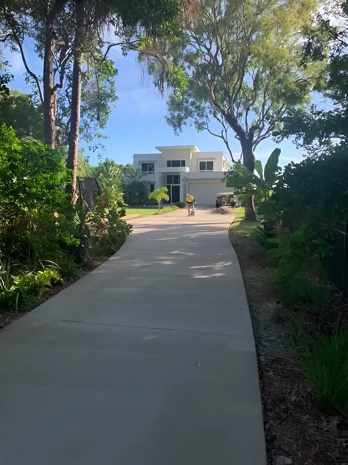 Long Driveway Leads to a White Modern House With a Green Lawn — Showcase Concrete & Polishing in Moore Park Beach, QLD