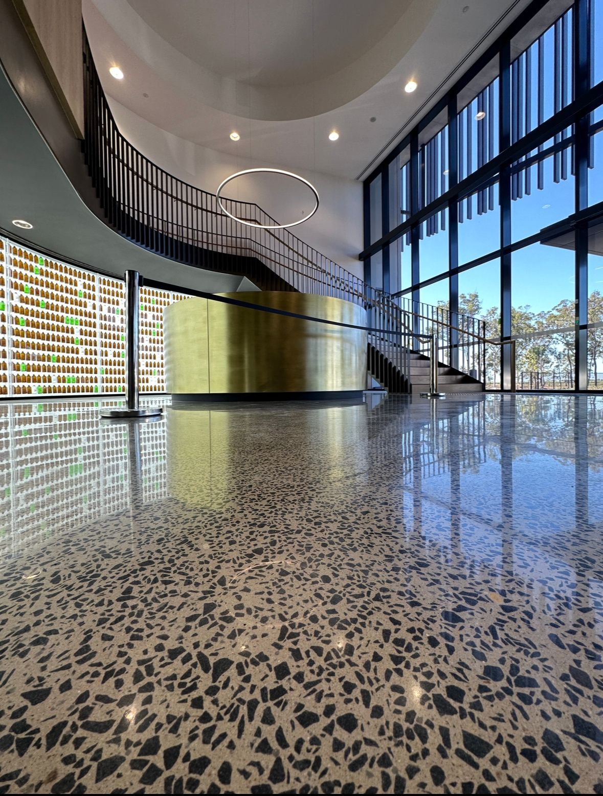 Polished concrete lobby with gold-colored curved structure, black staircase, and large windows. — Showcase Concrete & Polishing in Moore Park Beach, QLD