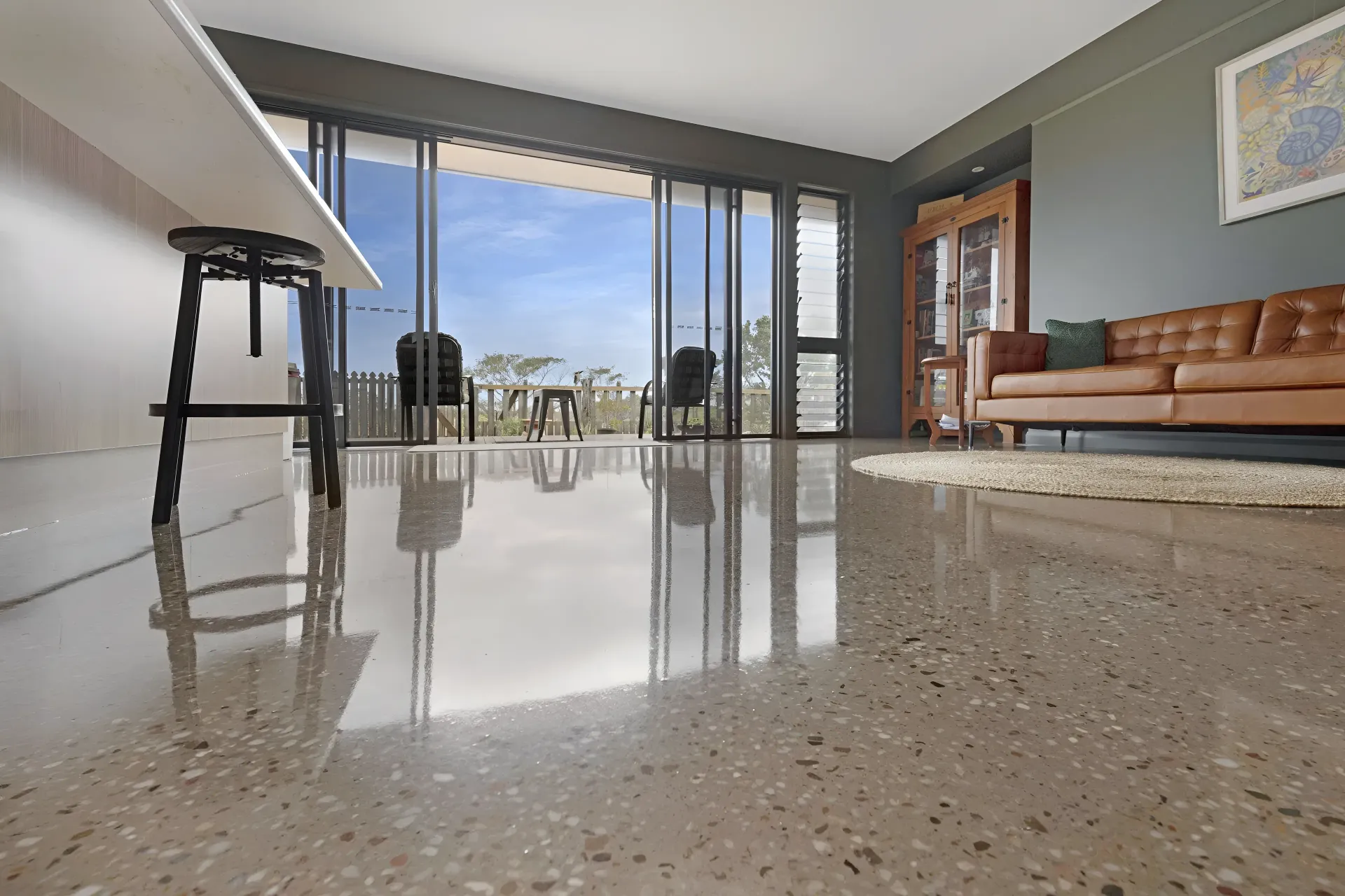 Polished Concrete Floor in Living Room With a Leather Couch — Showcase Concrete & Polishing in Moore Park Beach, QLD
