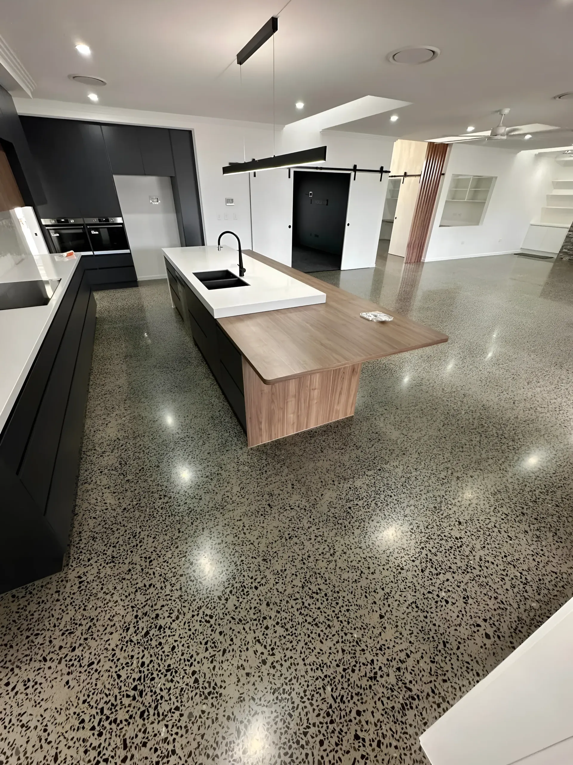 Modern Kitchen With Large Island, Concrete Floor and Dark Cabinets — Showcase Concrete & Polishing in Moore Park Beach, QLD