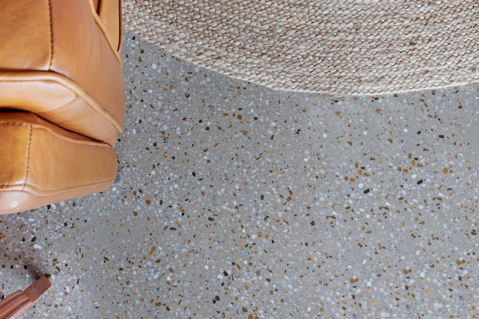 Tan leather shoe and woven mat on speckled gray flooring. — Showcase Concrete & Polishing in Moore Park Beach, QLD