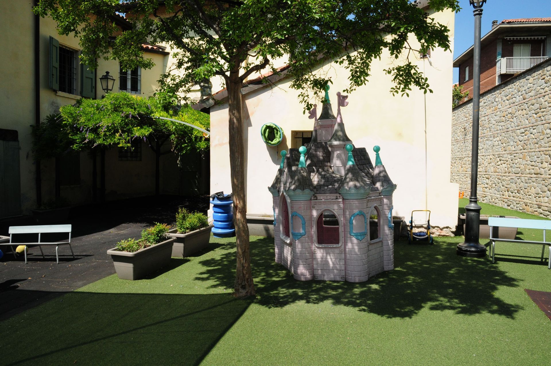 Una piccola casetta da gioco a forma di castello è situata sotto un albero