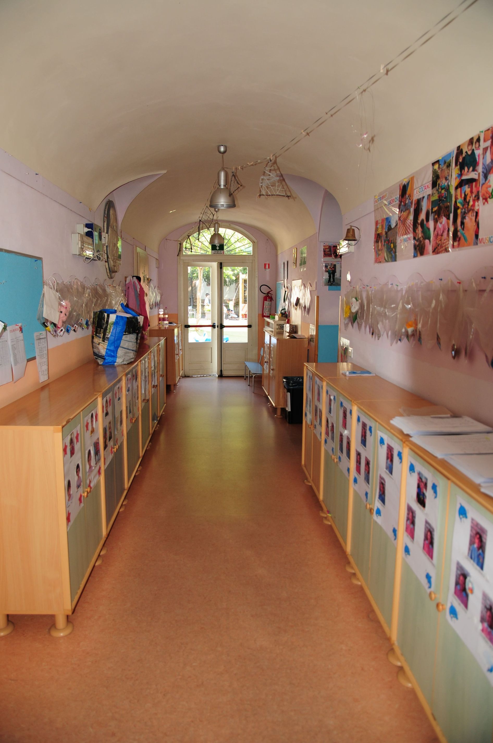 Un lungo corridoio con molti armadi e quadri alle pareti.
