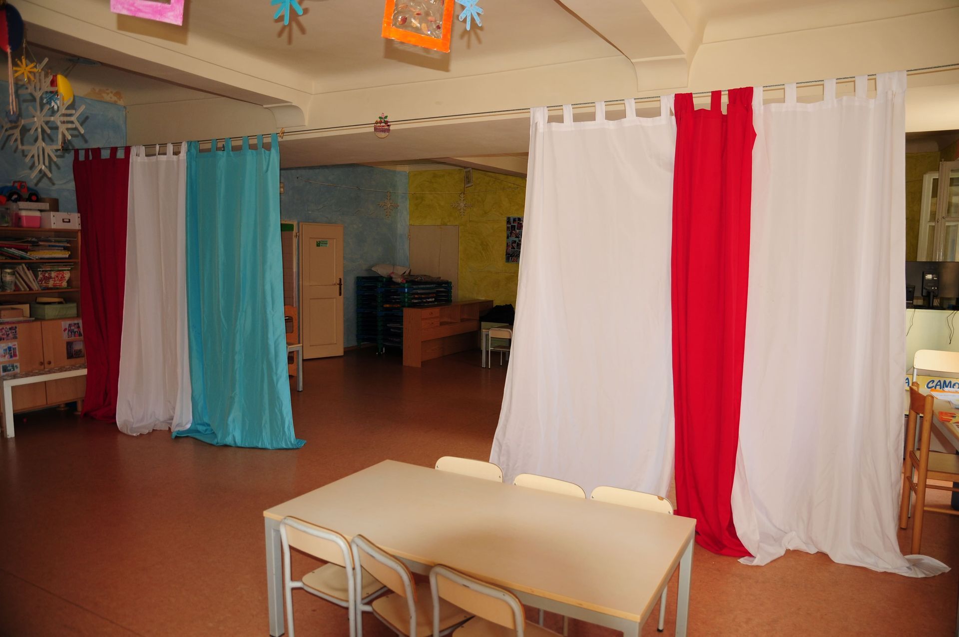 Una stanza con un tavolo, delle sedie e delle tende sul muro.