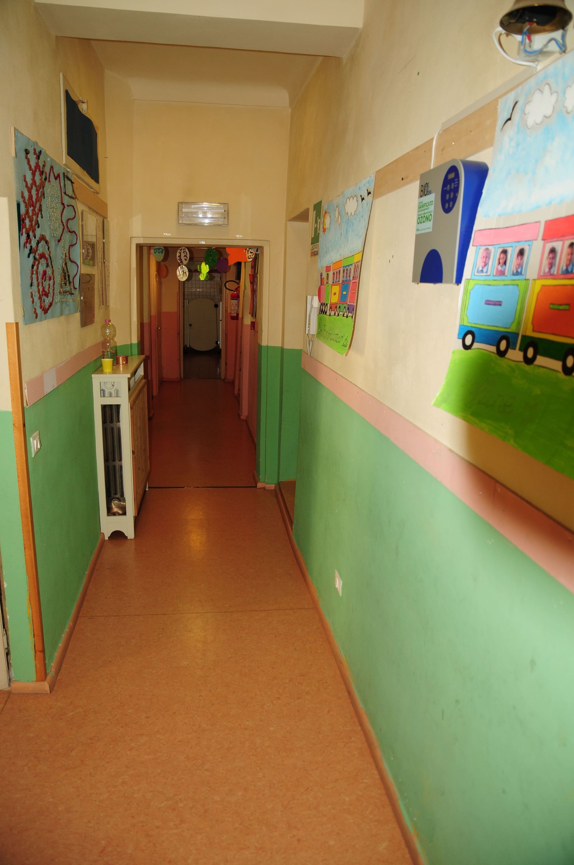 Un corridoio con pareti verdi e quadri sul muro