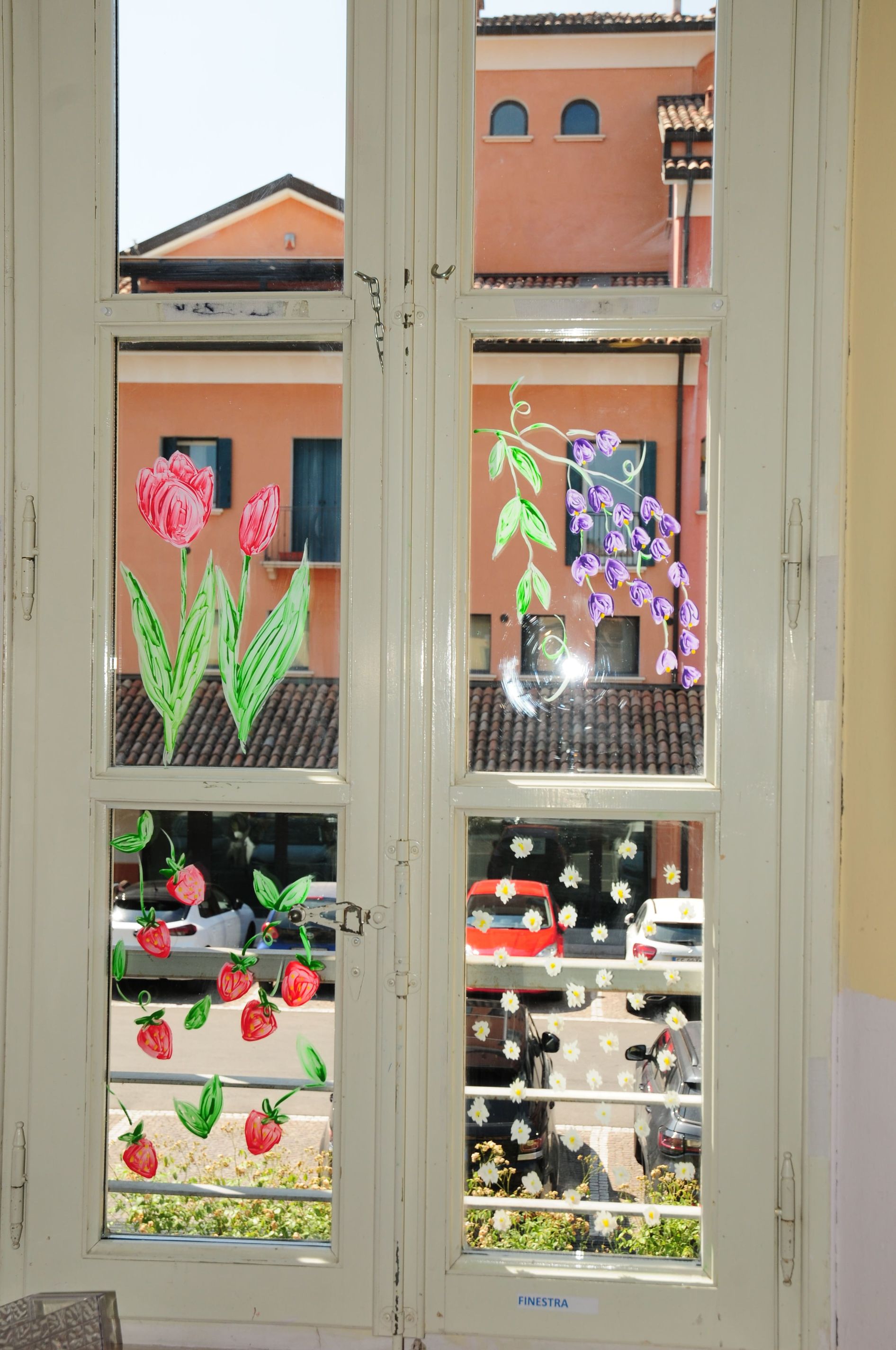 Una finestra bianca con dei fiori dipinti sopra