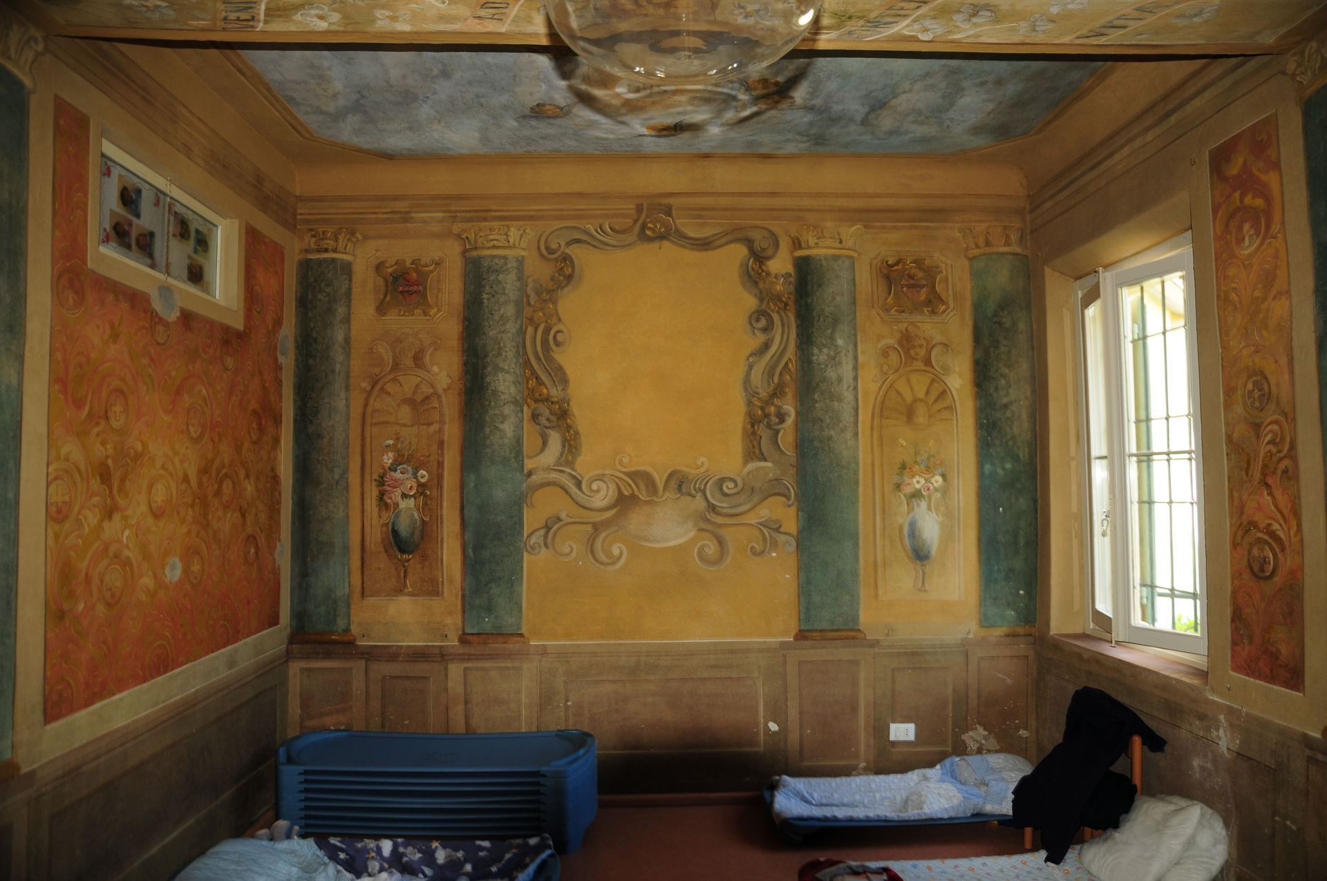 Una stanza con due letti e un lampadario sul soffitto.