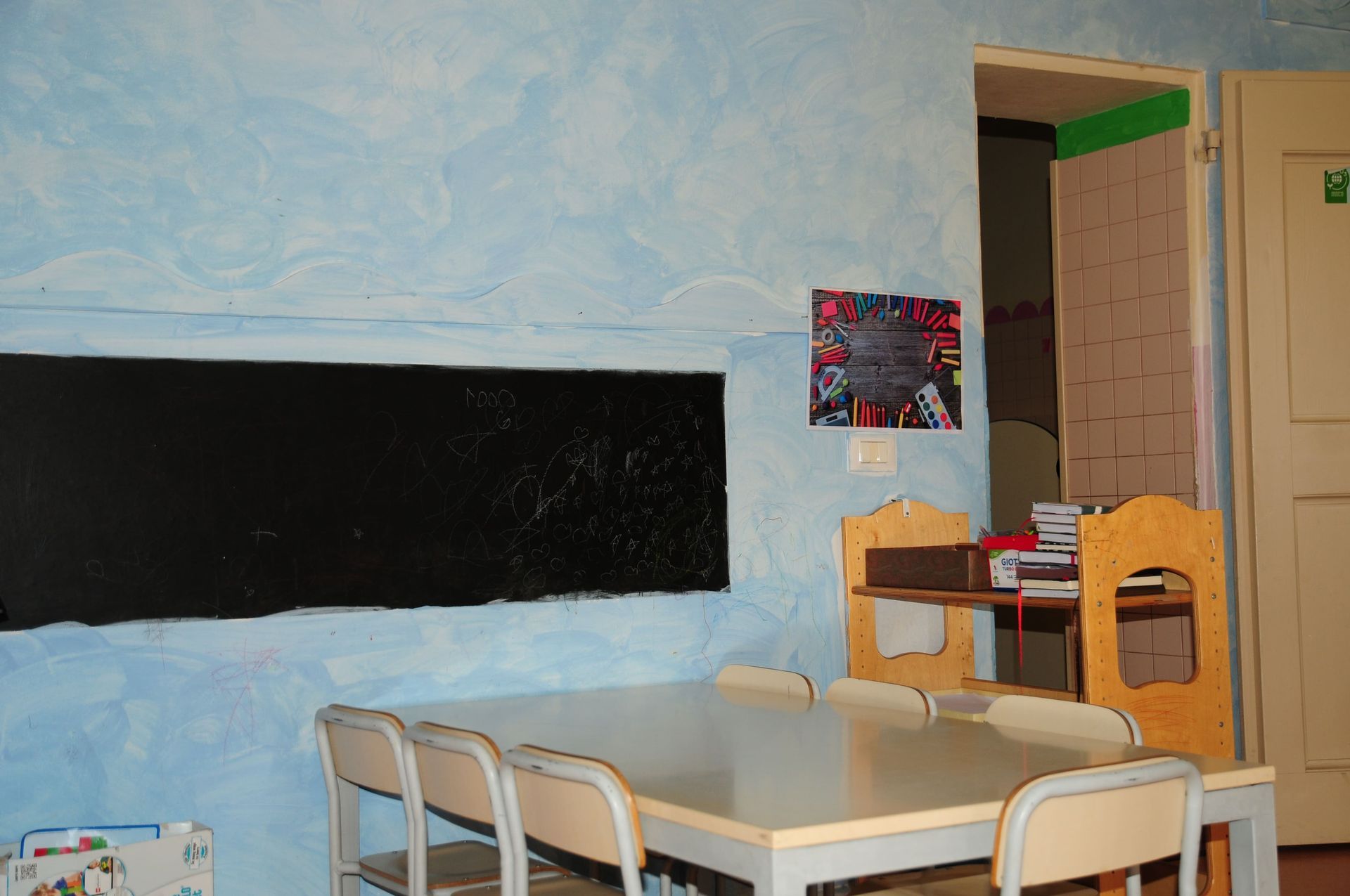 Una stanza con un tavolo e delle sedie e una lavagna sul muro