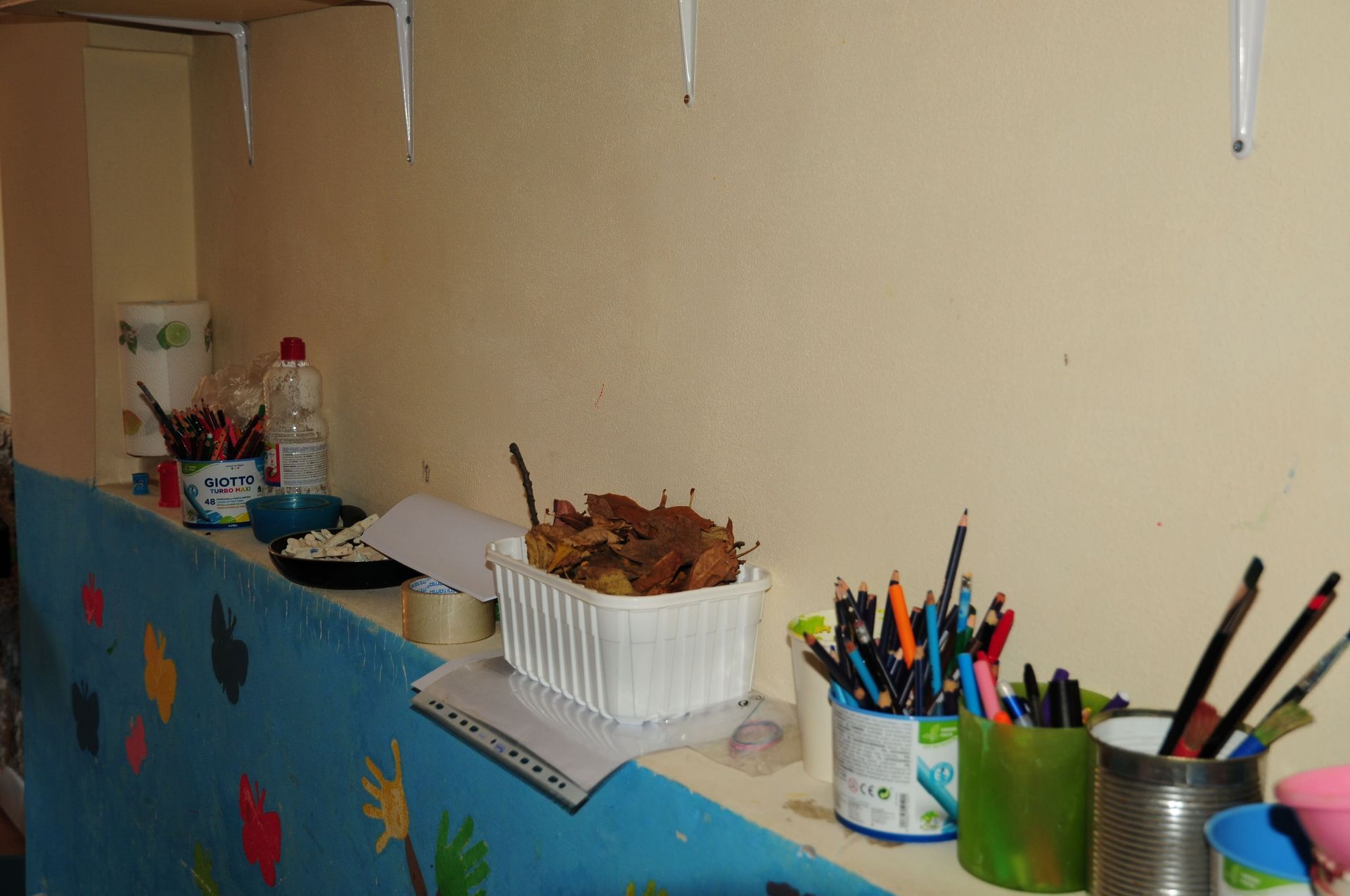 Uno scaffale con un cestino di foglie e matite sopra
