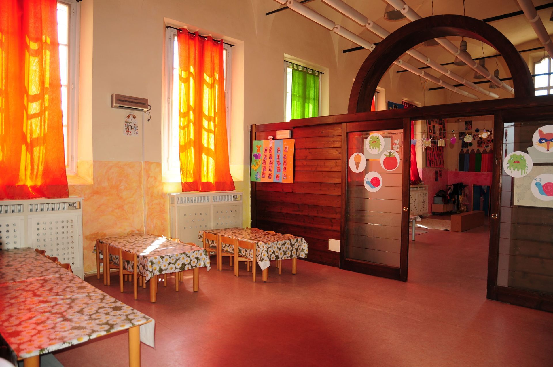 Una stanza con tavoli e sedie e vetrate colorate