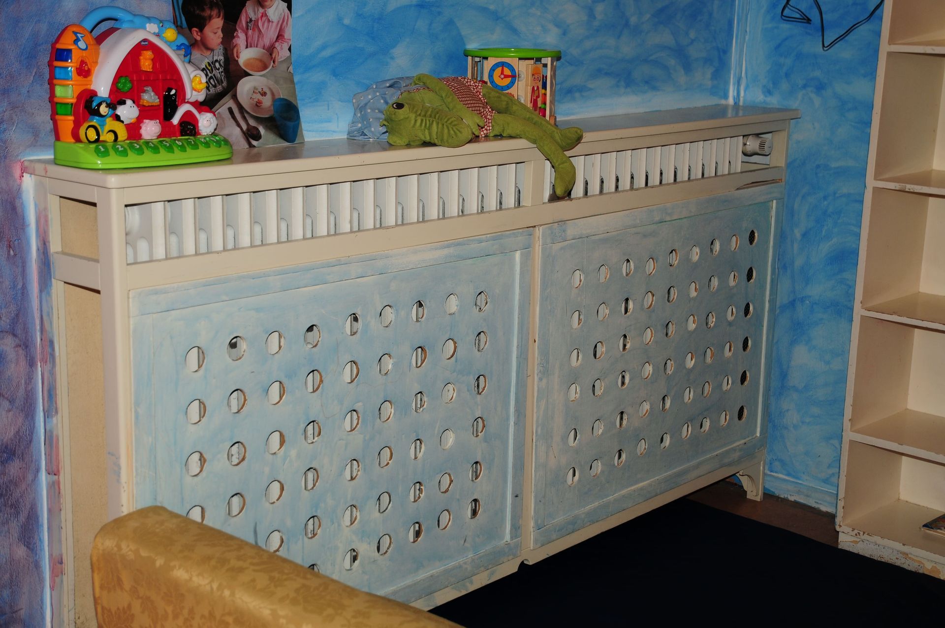 Una stanza per bambini con copritermosifone e giocattoli