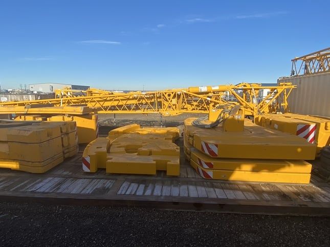 A picture of yellow crane rigging laying in a yard on mats.