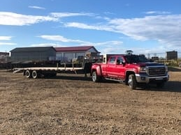 A picture of a red hotshot truck with a trailer in a yard in Grande Prairie