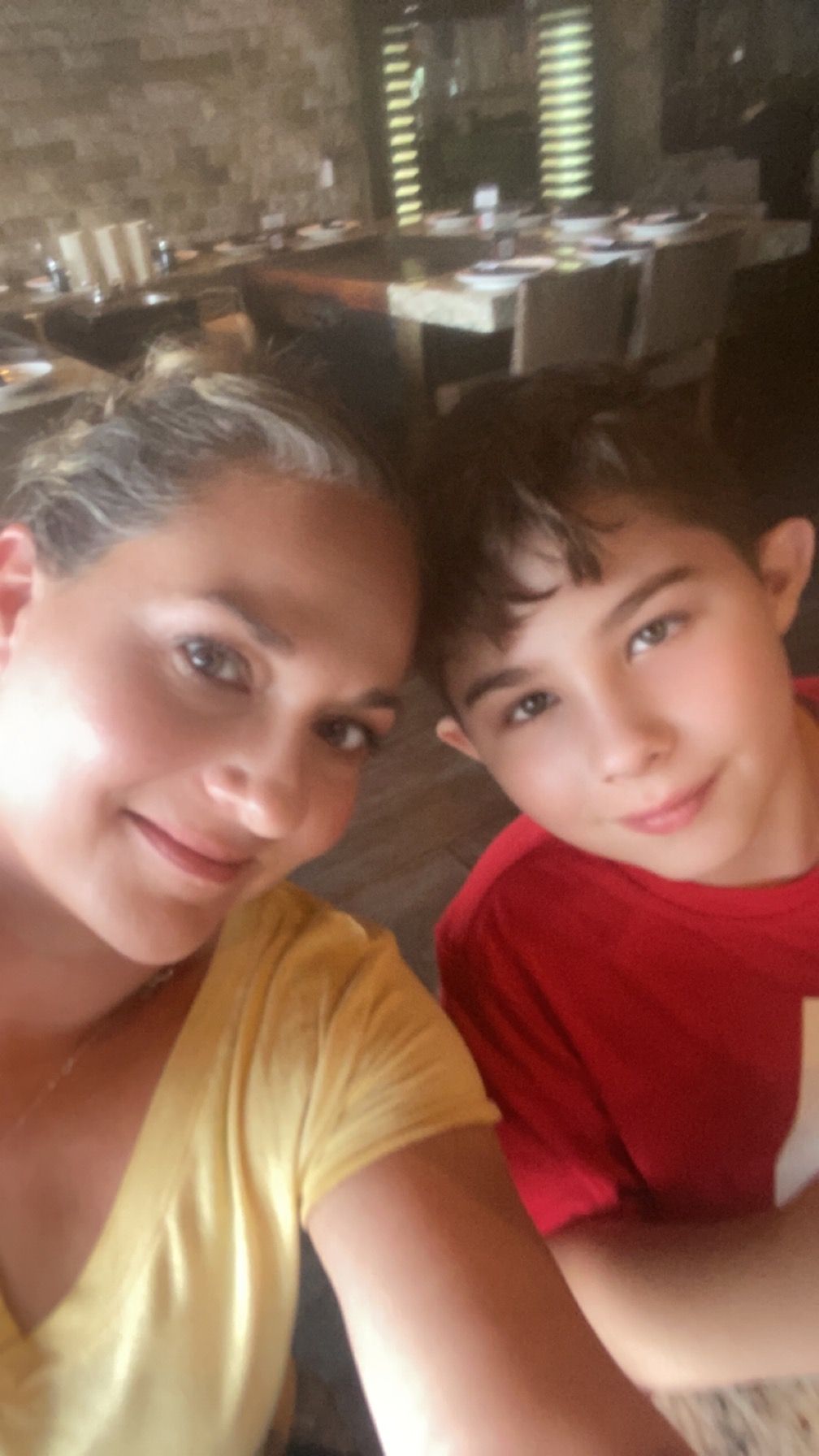 A woman and a boy are taking a selfie in a restaurant.