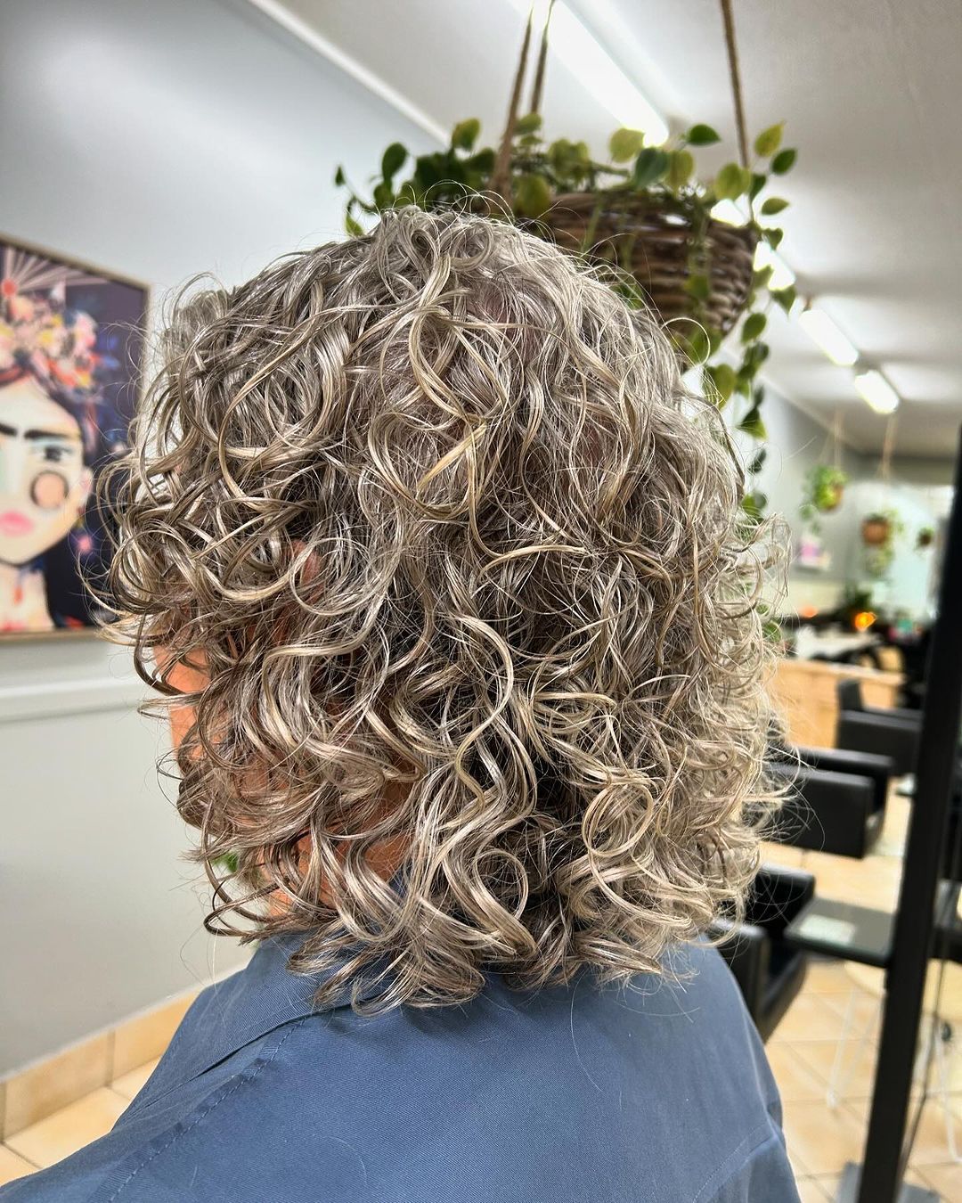 A woman with curly hair is getting her hair cut in a salon — M & Co Hair Salon In Atherton, QLD