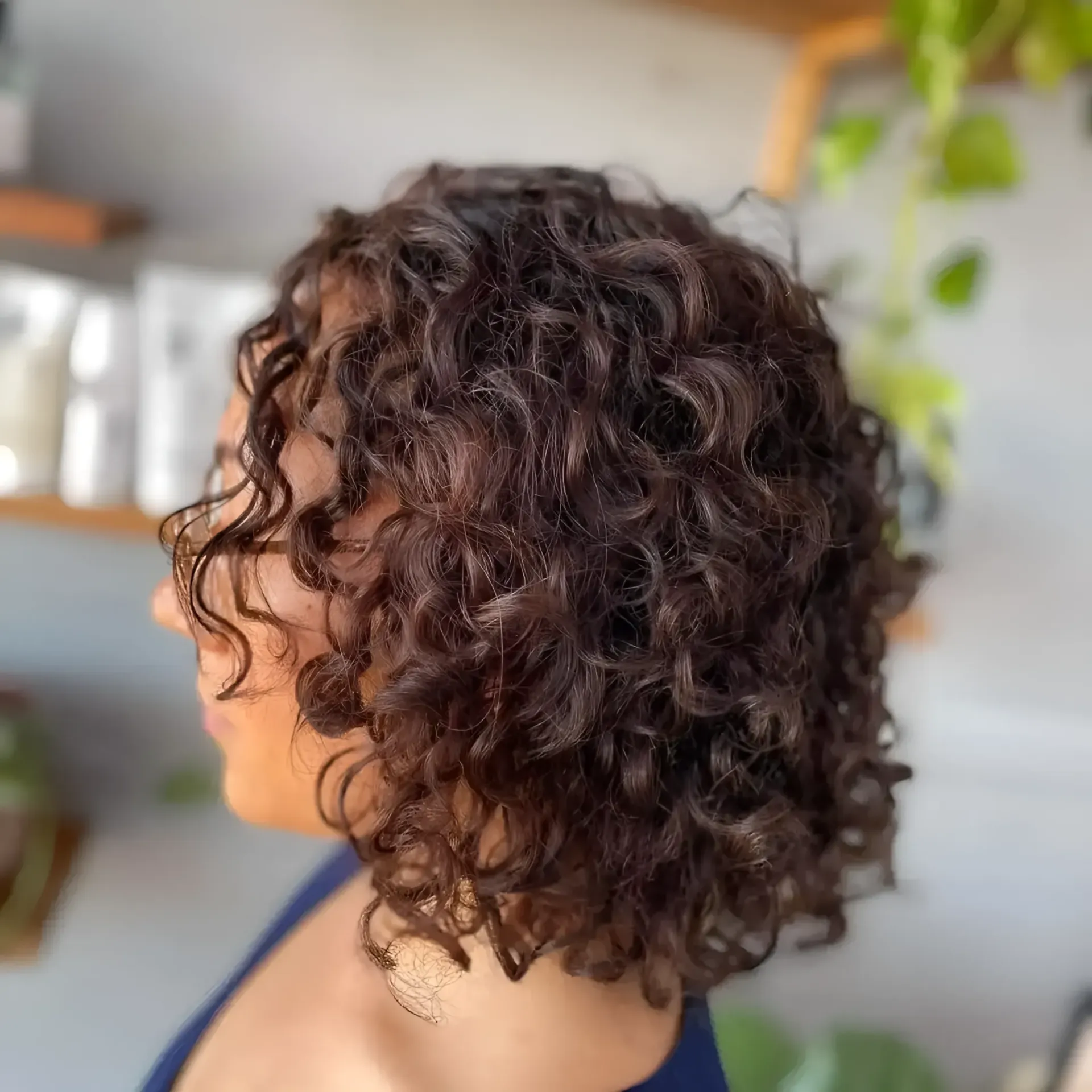 A woman with curly hair is wearing a blue shirt — M & Co Hair Salon In Atherton, QLD