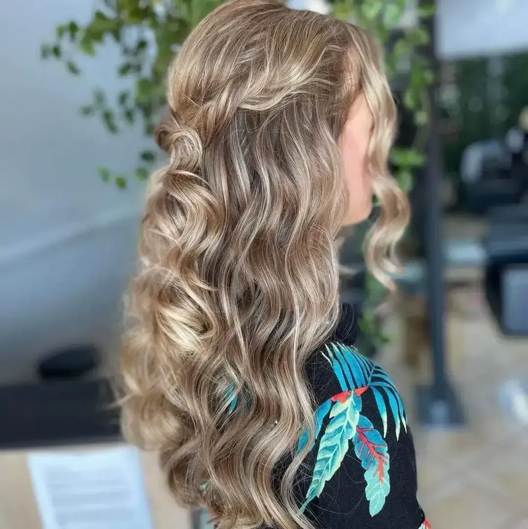 A woman with long blonde hair is wearing a half up half down hairstyle — M & Co Hair Salon In Atherton, QLD