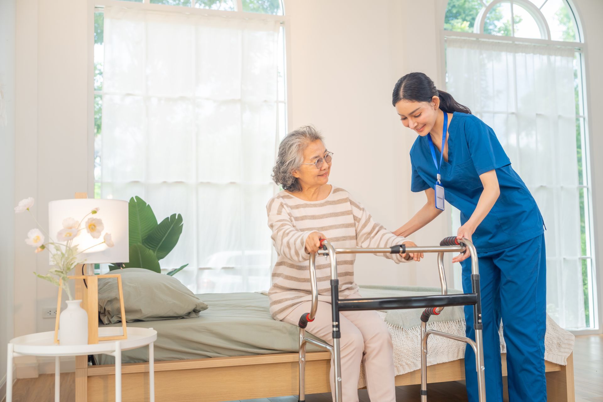Nurse assisting an elderly patient with a walker in a bright bedroom