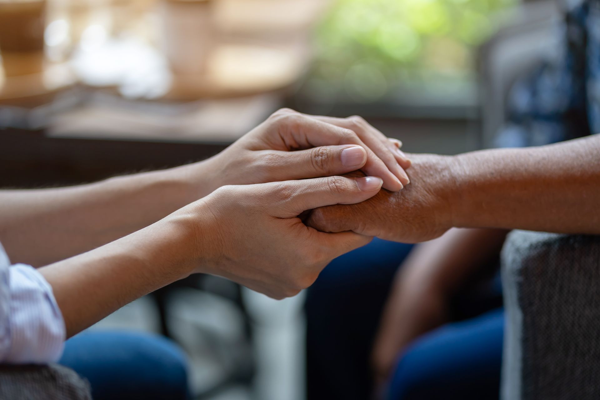 Hands gently clasped in support during a conversation indoors
