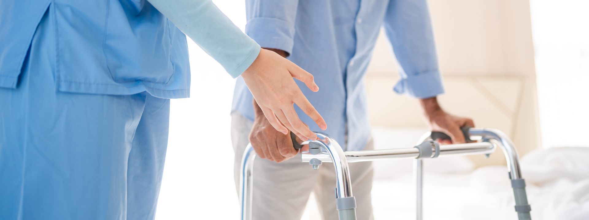 Nurse helping a patient use a walker in a bright hospital room