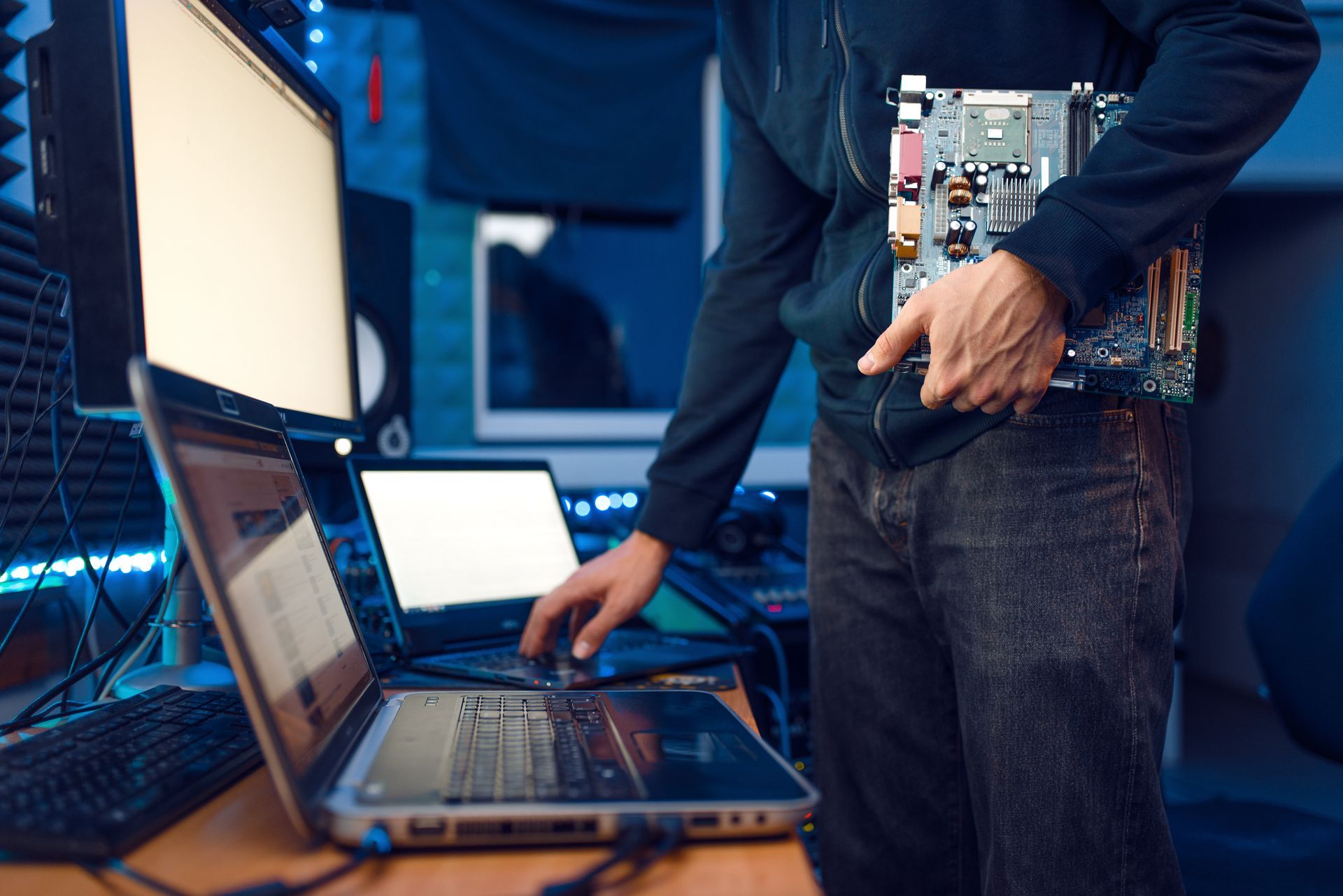 a man is holding a motherboard in front of a laptop