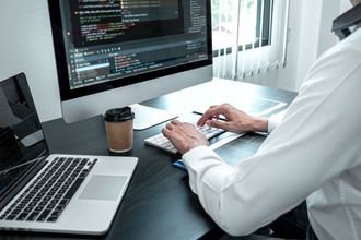 a man is typing on a keyboard in front of a computer