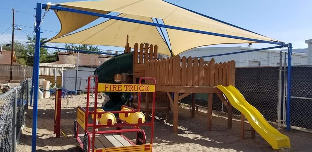 A playground with a house and a slide under a covered area.