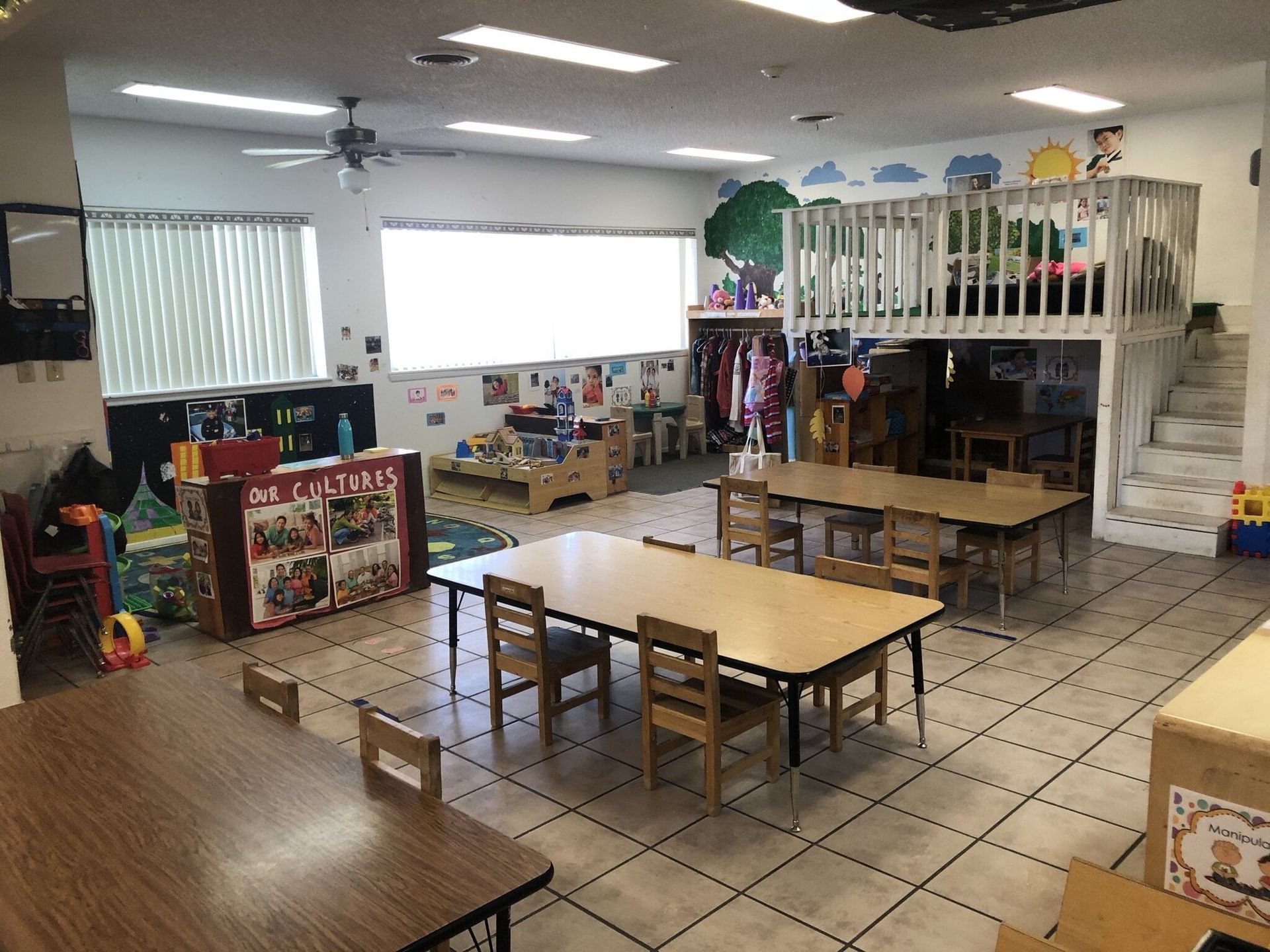 A classroom with tables and chairs and a play area.