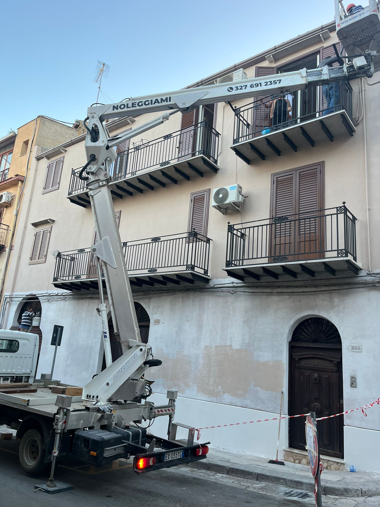 Piattaforma aerea e alta struttura metallica contro un cielo azzurro e terso.