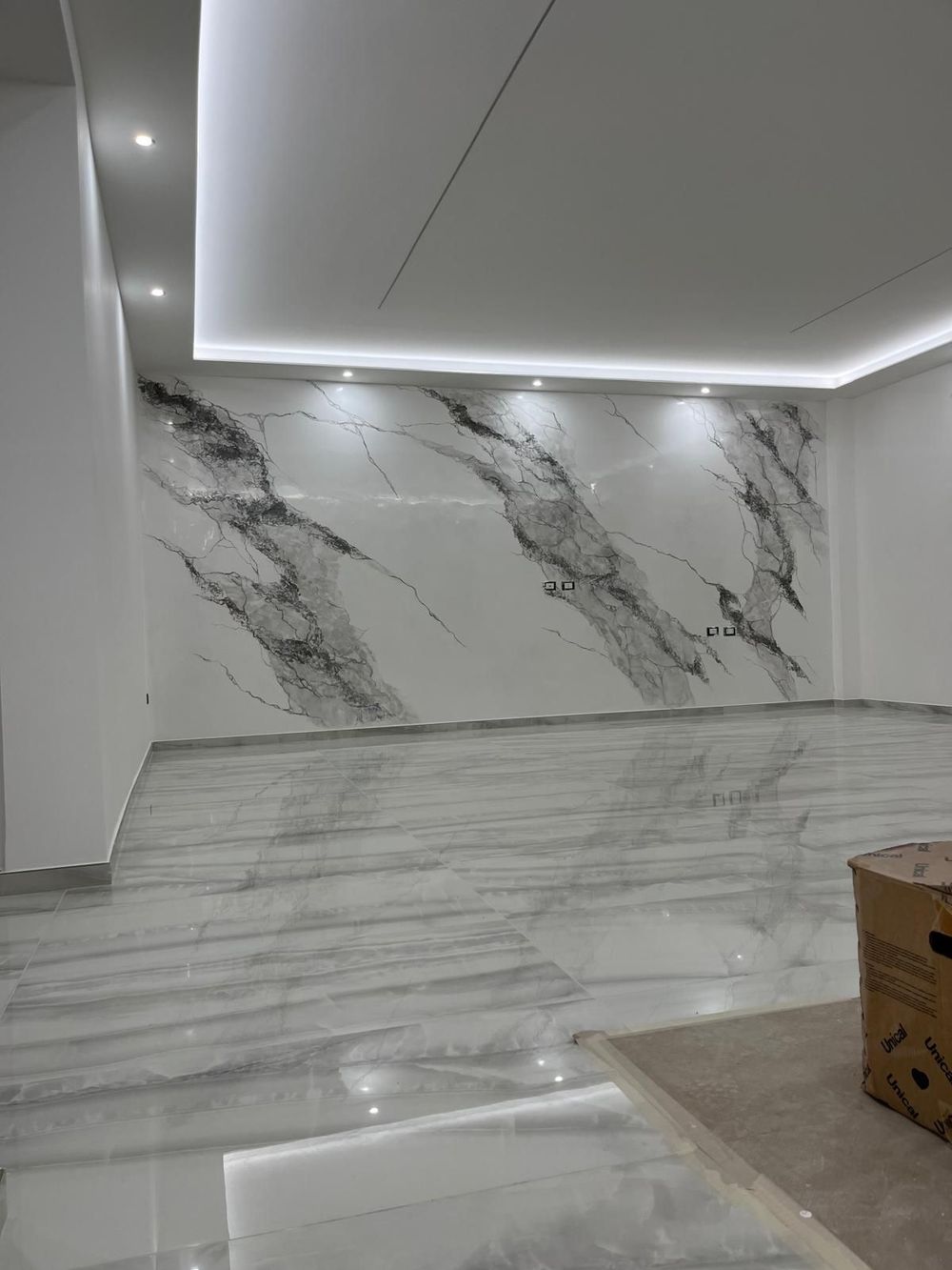 Cucina moderna con mobili bianchi, isola in legno, sgabelli neri, paraschizzi in marmo e ampia finestra.