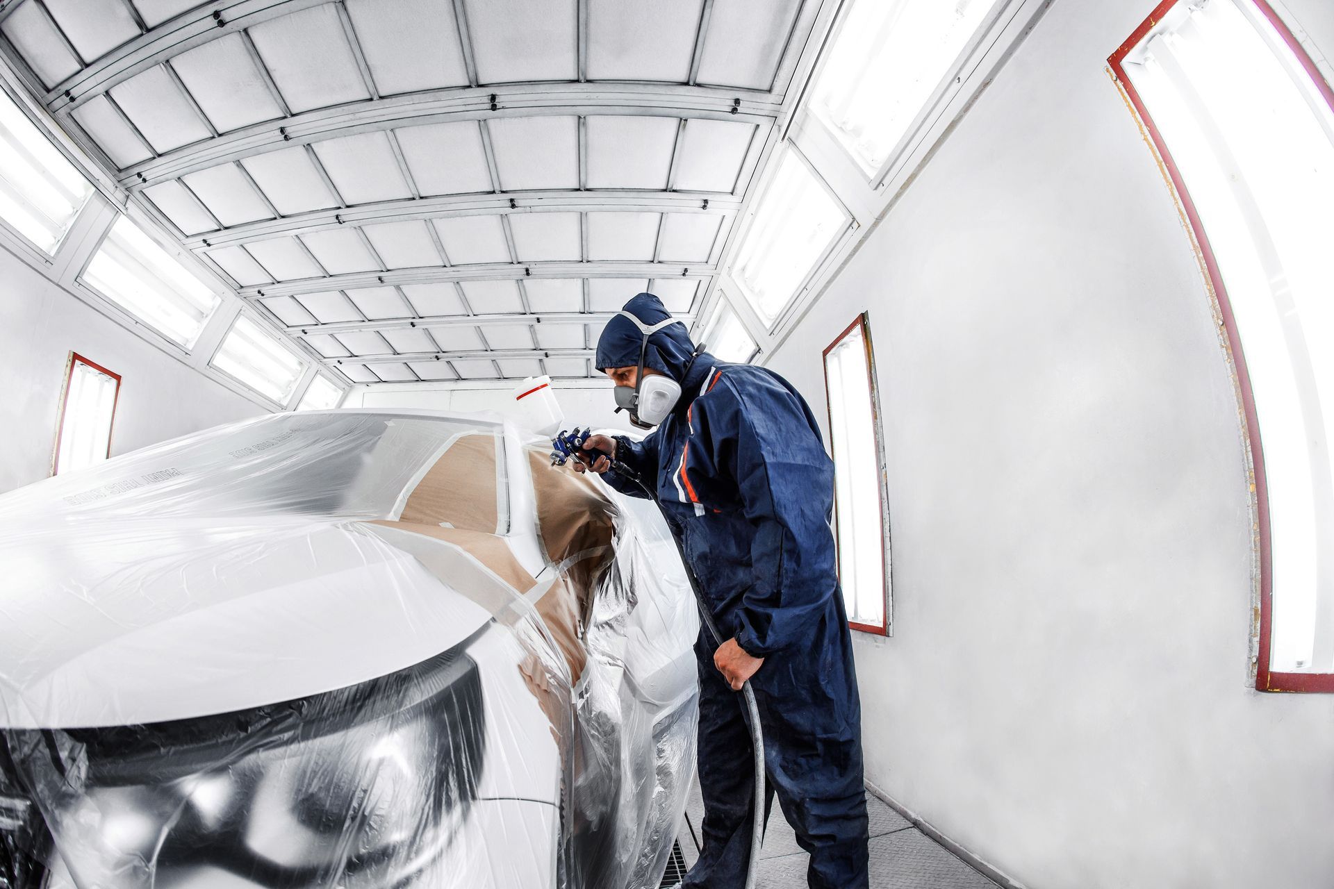 a man in a a spray booth paints a car