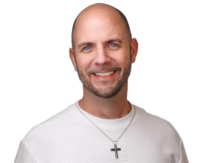 A man and a woman are sitting on a dock overlooking a lake.