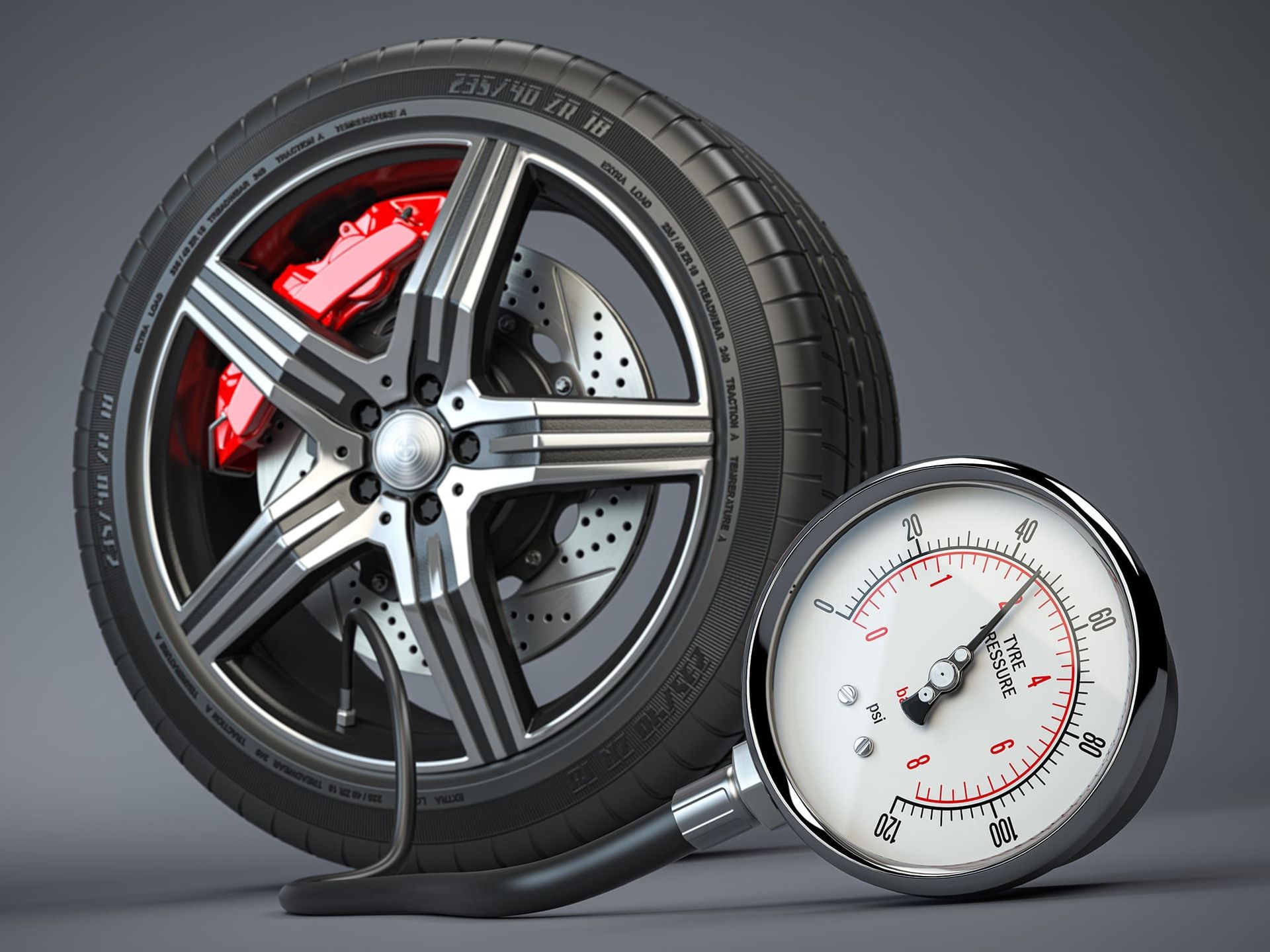 Car tire with red brake caliper next to a tire pressure gauge.