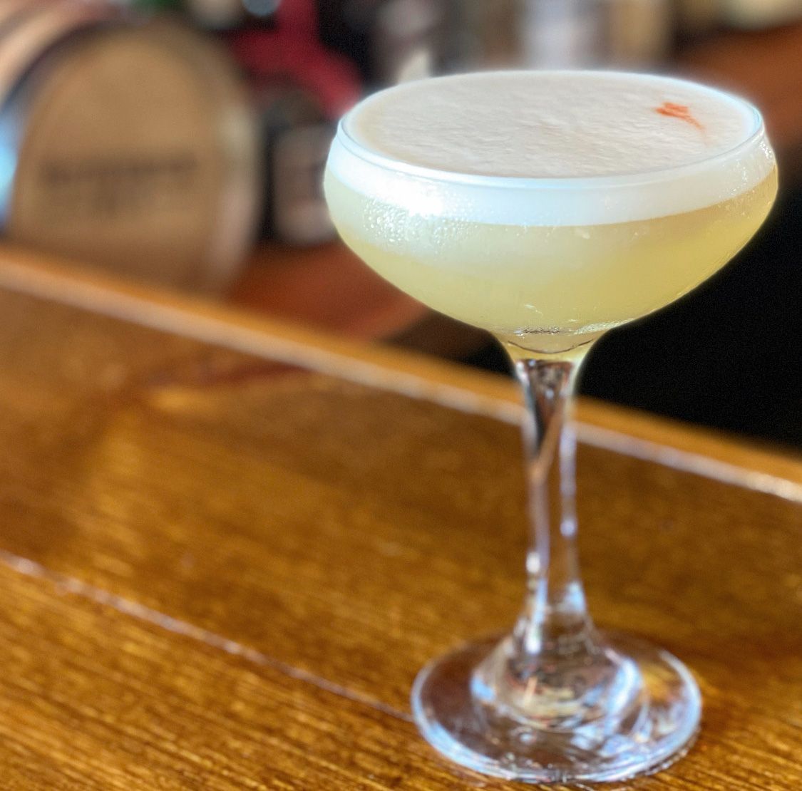 A close up of a cocktail in a wine glass on a bar