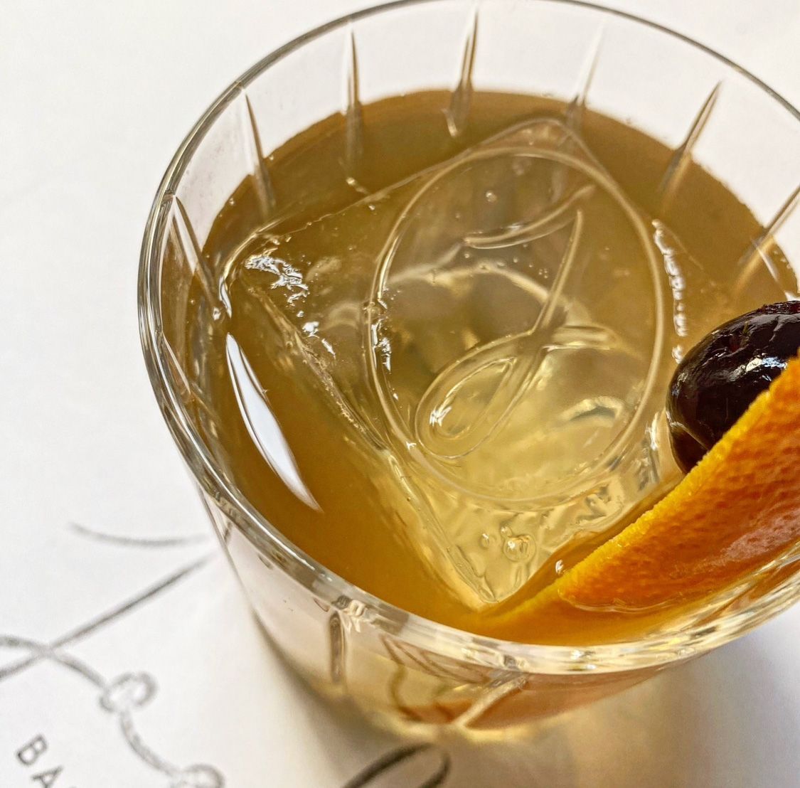 A close up of a glass of liquid with a slice of orange in it