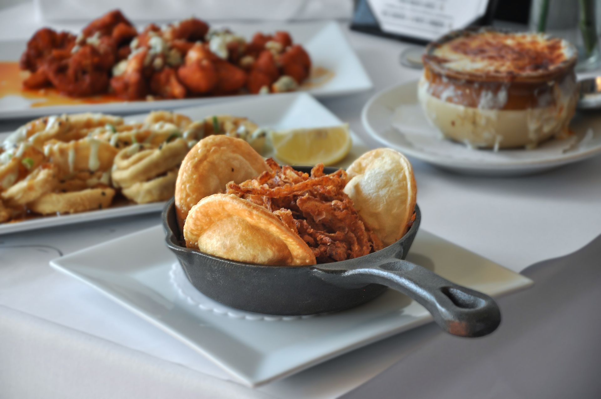 A small skillet filled with french fries sits on a white plate on a table.
