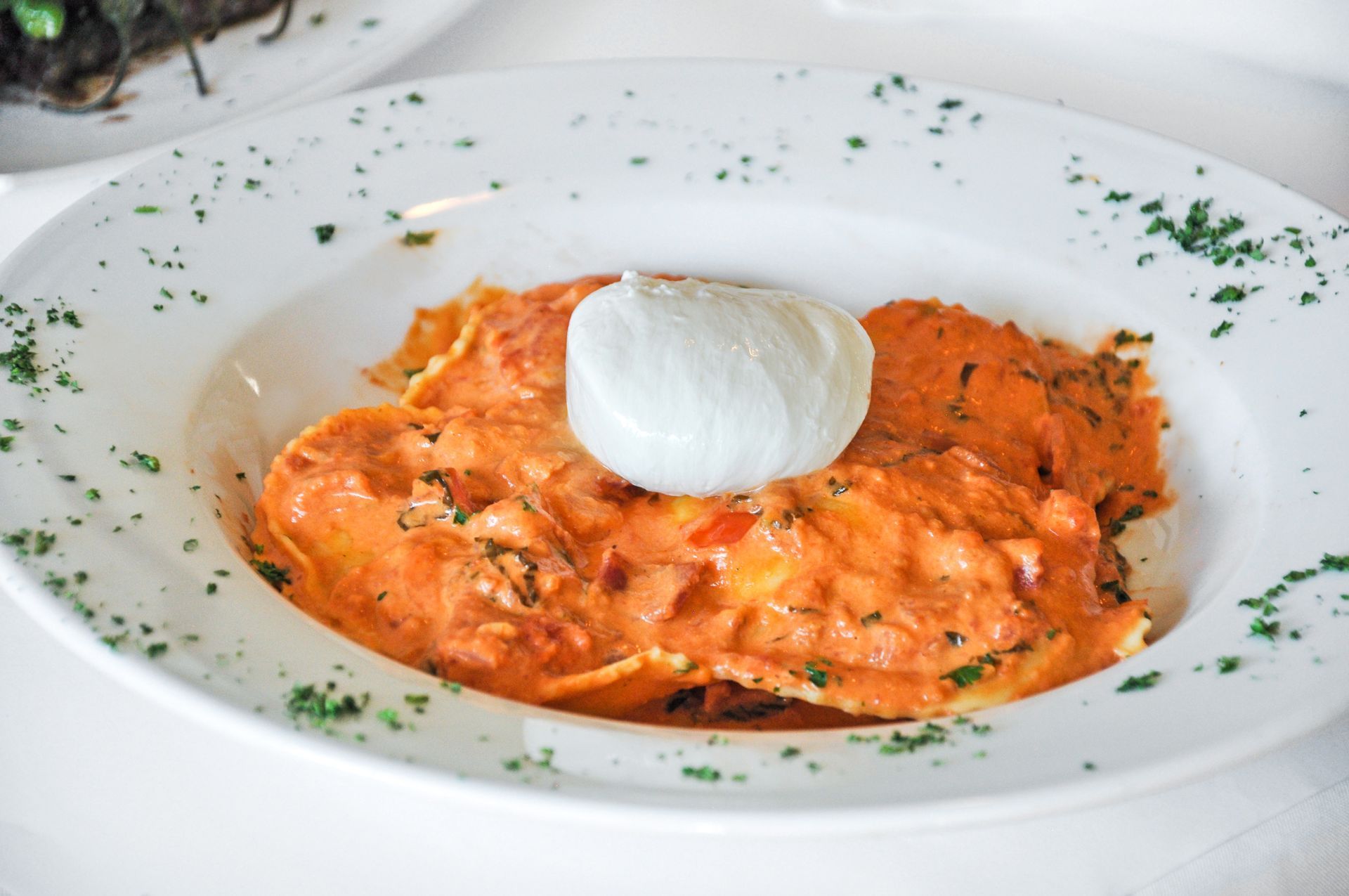 A white plate topped with ravioli and a piece of mozzarella cheese.