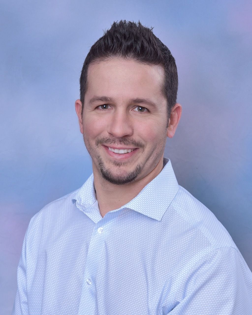 A man is holding a dog in his arms and the dog is wearing a sweater.