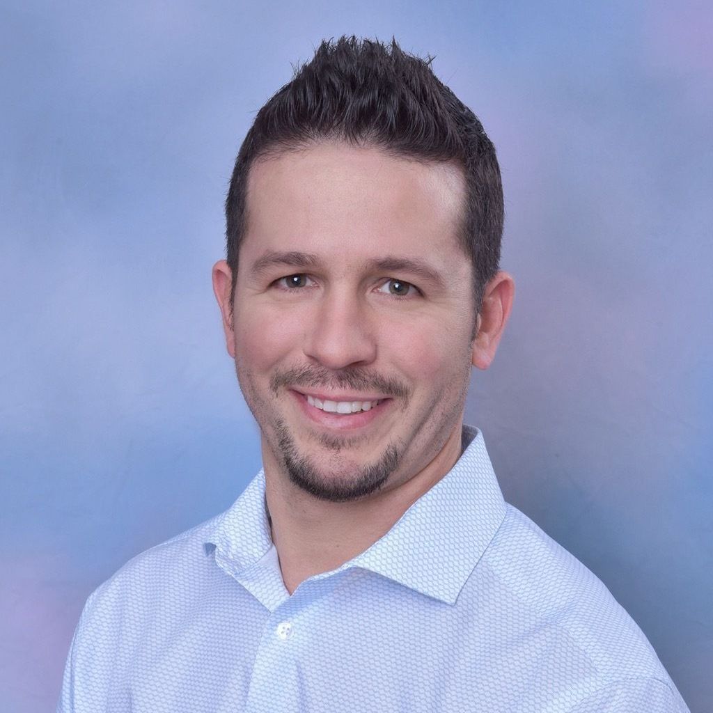 A man and a woman are sitting on a dock overlooking a lake.