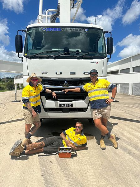 Three Men Are Posing for A Picture in Front of A Truck — Mass Construction Group Australia Pty Ltd in South Mackay, QLD