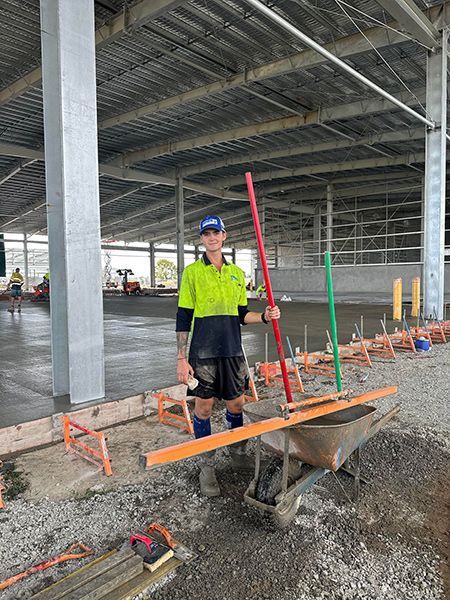 A Man Is Standing Next to A Wheelbarrow Holding a Broom — Mass Construction Group Australia Pty Ltd in South Mackay, QLD