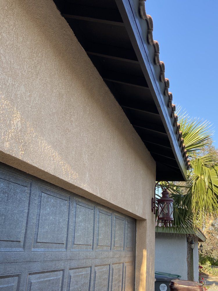 Tan stucco garage with brown trim and roof. A red lantern is mounted on the side.