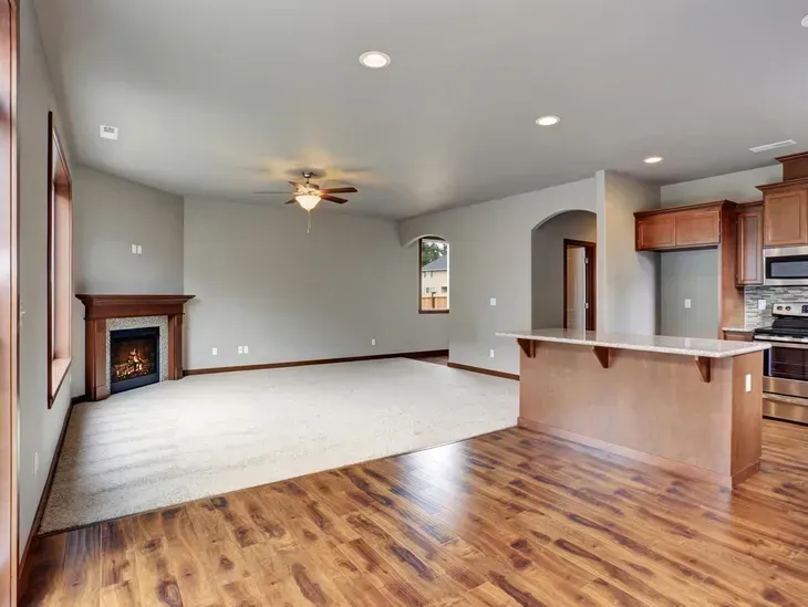 An empty living room with hardwood floors and a fireplace.