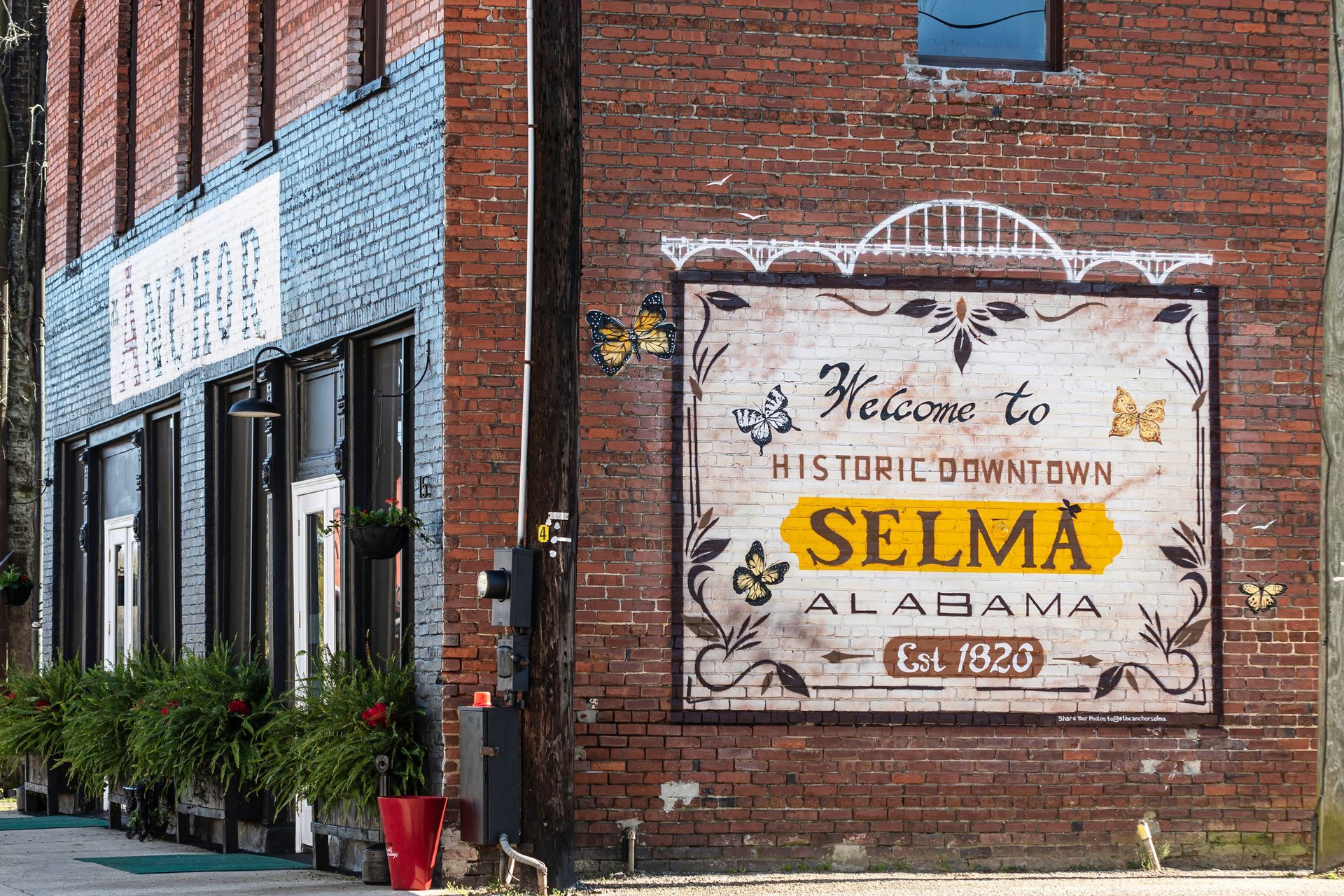 A sign on the side of a brick building welcomes people to selma alabama.
